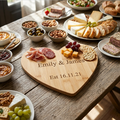 A personalised heart-shaped wooden charcuterie board engraved with the names 'Emily & James' and 'Est 16.11.21. Made from bamboo and perfect as a wedding gift.
