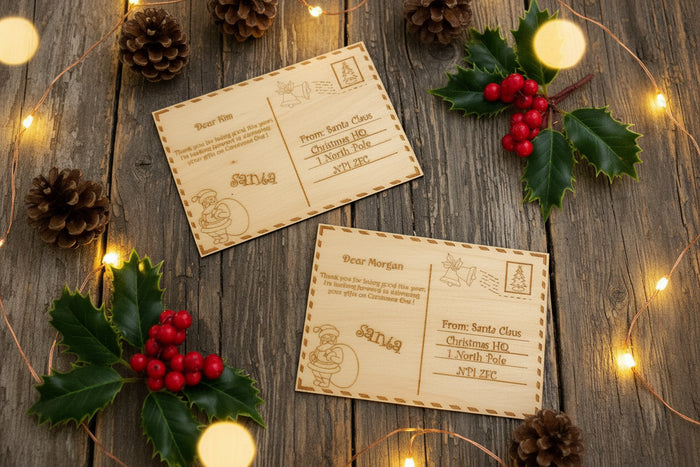 Two wooden letters addressed to Santa Claus on a rustic wood background with pine cones, berries and lights.