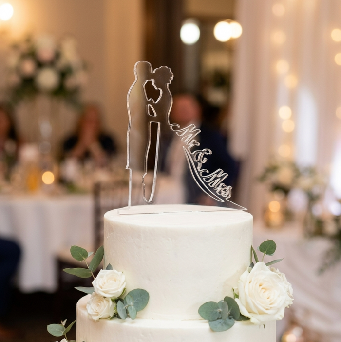 A wedding cake with an acrylic cake topper of a bride and groom and the words Mr & Mrs