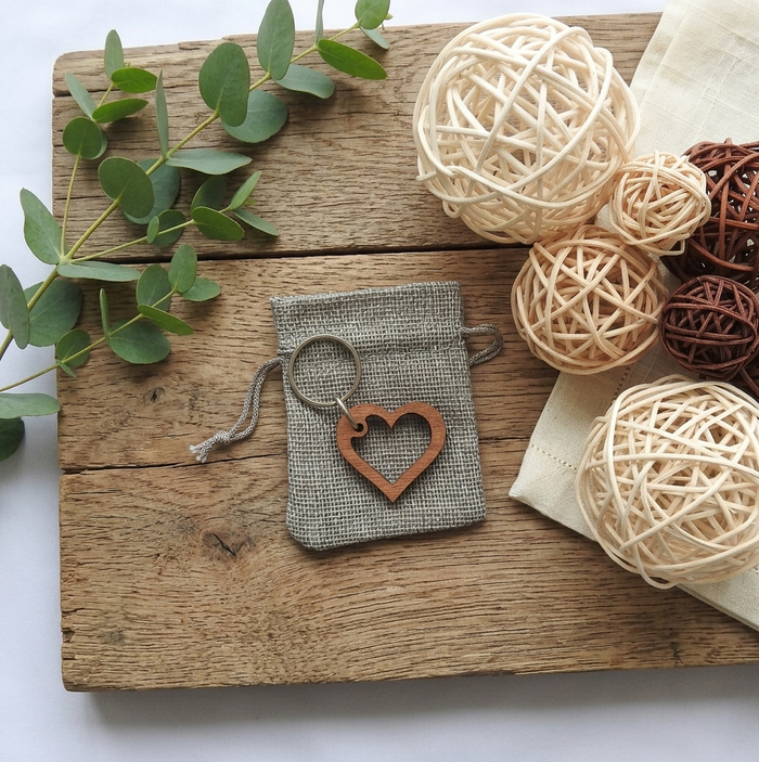 A hardwood heart keychain on a grey hessian gift bag. Placed on a rustic board with decorations