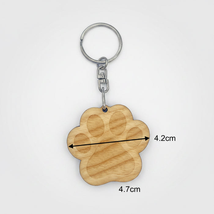 Wooden paw-shaped keychain with measurements on a light gray background