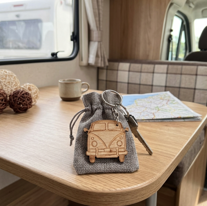 A solid hardwood camper van shaped keychain is on a table in a motorhome.